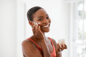 A woman applies lotion to her face