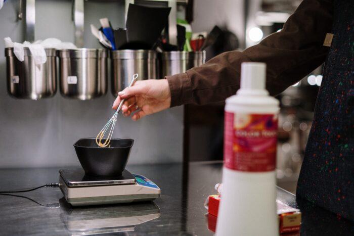 Womans hand mixing professional color in a bowl